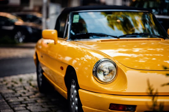 Exposition intérieure d'une voiture de collection rouge dans un showroom aux rideaux sombres, éclairage professionnel mettant en valeur le véhicule sur parquet bois